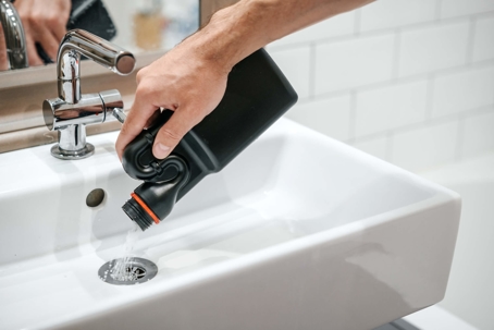 man pouring liquid drain cleaner down bathroom sink